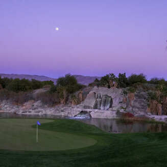 Lush green fairway with desert mountains in the background under a clear blue sky at Eagle Falls Golf Course, Indio, California.