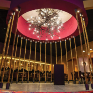 The Agua Caliente Casino Cathedral City entrance is illuminated at night with vibrant purple and blue lights, featuring the casino's name prominently displayed.