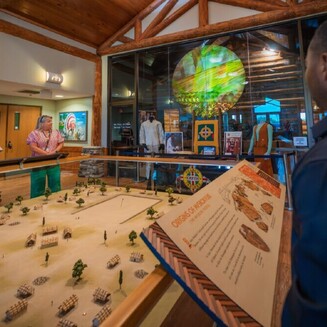 Museum visitors observe various miniature village within a bright, spacious room at the Poarch Creek Indians Museum & Gift Shop.