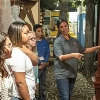 Museum guide speaks to a group beside Poarch Creek cultural artifacts display at the Poarch Creek Indians Museum.